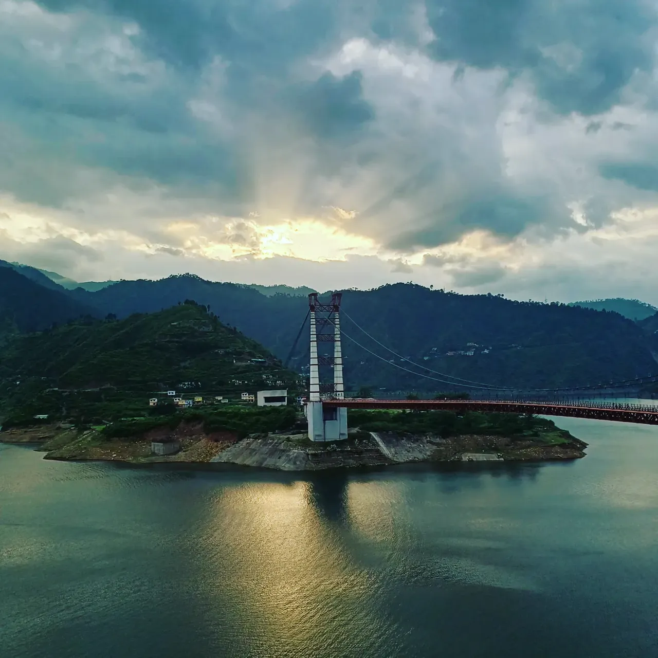 Daytime view of Dobra Chanti bridge surrounded by hills and blue water